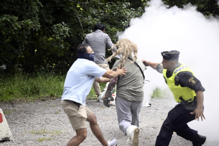 A woman interrupts a Quran-burning protest in Sweden by spraying activist with a fire extinguisher